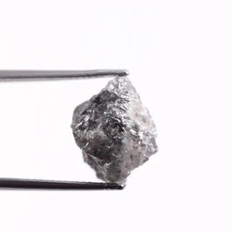 A collection of grey diamonds with varying shades of grey, from light silver to dark graphite, displaying their natural mineral inclusions.