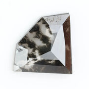 Geometric cut salt and pepper lab grown diamond with smoky black and white inclusions, showcasing a unique faceted shape and modern ethical gemstone design on a clean white background