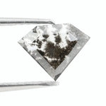 Geometric cut salt and pepper lab grown diamond with smoky black and white inclusions, showcasing a unique faceted shape and modern ethical gemstone design on a clean white background