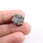 A side view of a grey diamond engagement ring, featuring the gem's distinctive speckles and smoky hues, set in platinum.