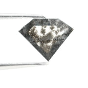 Geometric cut salt and pepper lab grown diamond with smoky black and white inclusions, showcasing a unique faceted shape and modern ethical gemstone design on a clean white background