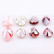 Eight faceted lab grown colored diamonds in pear, oval, and marquise cuts featuring fancy pink, yellow, and deep red tones arranged on a white background.