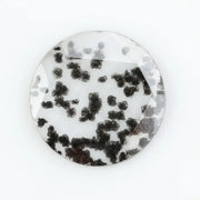 Close-up of a round, lab-grown diamond with black and white speckled inclusions, sparkling facets, and jewelry-grade clarity, ethically sourced and crafted for fine jewelry