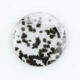 Close-up of a round, lab-grown diamond with black and white speckled inclusions, sparkling facets, and jewelry-grade clarity, ethically sourced and crafted for fine jewelry