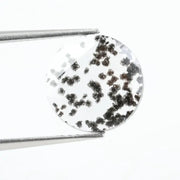 Close-up of a round, lab-grown diamond with black and white speckled inclusions, sparkling facets, and jewelry-grade clarity, ethically sourced and crafted for fine jewelry