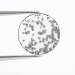 Close-up of a round, lab-grown diamond with black and white speckled inclusions, sparkling facets, and jewelry-grade clarity, ethically sourced and crafted for fine jewelry