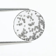 Close-up of a round, lab-grown diamond with black and white speckled inclusions, sparkling facets, and jewelry-grade clarity, ethically sourced and crafted for fine jewelry