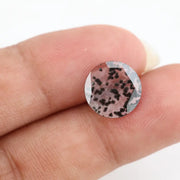 Close-up of a round, lab-grown diamond with black and white speckled inclusions, sparkling facets, and jewelry-grade clarity, ethically sourced and crafted for fine jewelry