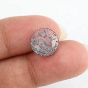 Close-up of a round, lab-grown diamond with black and white speckled inclusions, sparkling facets, and jewelry-grade clarity, ethically sourced and crafted for fine jewelry