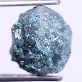 Raw blue diamond held by tweezers on a white background