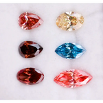 Six fancy color lab grown diamonds on white background including yellow oval cut, blue marquise cut, pink marquise cut, peach pear cut, deep red pear cut, and red oval cut brilliant stones for custom jewelry design.