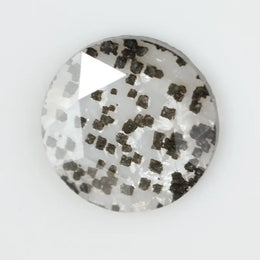 Close-up of a unique lab-grown diamond featuring distinct black carbon inclusions, showcasing its natural beauty and sustainable origins.