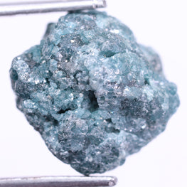 Raw blue diamond held by tweezers on a white background