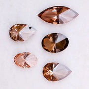 Five lab grown brown and champagne diamonds in pear, oval, and marquise cuts displayed on a white background, showcasing rich cognac tones and brilliant faceting for fine jewelry design.