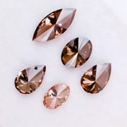 Five lab grown brown and champagne diamonds in pear, oval, and marquise cuts displayed on a white background, showcasing rich cognac tones and brilliant faceting for fine jewelry design.
