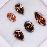 Five lab grown brown and champagne diamonds in pear, oval, and marquise cuts displayed on a white background, showcasing rich cognac tones and brilliant faceting for fine jewelry design.