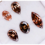 Five lab grown brown and champagne diamonds in pear, oval, and marquise cuts displayed on a white background, showcasing rich cognac tones and brilliant faceting for fine jewelry design.