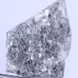 Raw diamond held between tweezers on a light purple background