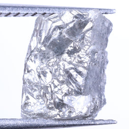 Raw diamond held by tweezers on a white background