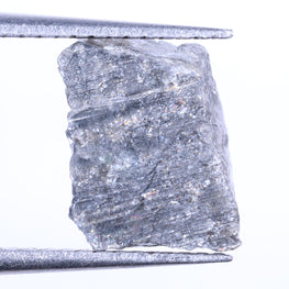 Raw diamond held between tweezers on a white background
