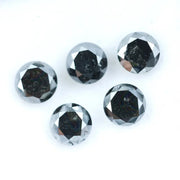 Five natural round cut black diamonds with faceted surfaces showing natural inclusions and dark carbon tones, loose untreated genuine diamonds suitable for custom jewelry making.