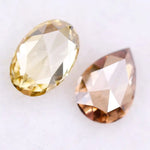 Two lab grown diamonds displayed on white background, including a fancy light yellow oval cut diamond labeled 1 and a champagne pear shaped diamond labeled 2, sustainably created loose stones for engagement rings.