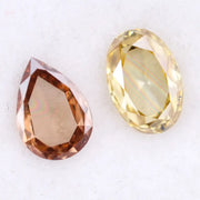 Two lab grown diamonds displayed on white background, including a fancy light yellow oval cut diamond labeled 1 and a champagne pear shaped diamond labeled 2, sustainably created loose stones for engagement rings.