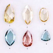 Six lab grown colored diamonds displayed on white background featuring pear, marquise and oval cuts in fancy yellow, champagne, blue and pink shades, ideal for custom engagement rings and fine jewelry settings.