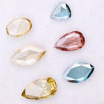 Six lab grown colored diamonds displayed on white background featuring pear, marquise and oval cuts in fancy yellow, champagne, blue and pink shades, ideal for custom engagement rings and fine jewelry settings.