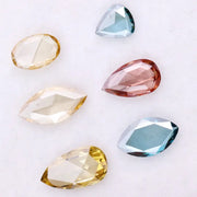 Six lab grown colored diamonds displayed on white background featuring pear, marquise and oval cuts in fancy yellow, champagne, blue and pink shades, ideal for custom engagement rings and fine jewelry settings.