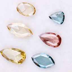 Six lab grown colored diamonds displayed on white background featuring pear, marquise and oval cuts in fancy yellow, champagne, blue and pink shades, ideal for custom engagement rings and fine jewelry settings.