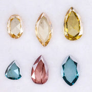 Six lab grown colored diamonds displayed on white background featuring pear, marquise and oval cuts in fancy yellow, champagne, blue and pink shades, ideal for custom engagement rings and fine jewelry settings.