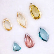 Six lab grown colored diamonds displayed on white background featuring pear, marquise and oval cuts in fancy yellow, champagne, blue and pink shades, ideal for custom engagement rings and fine jewelry settings.