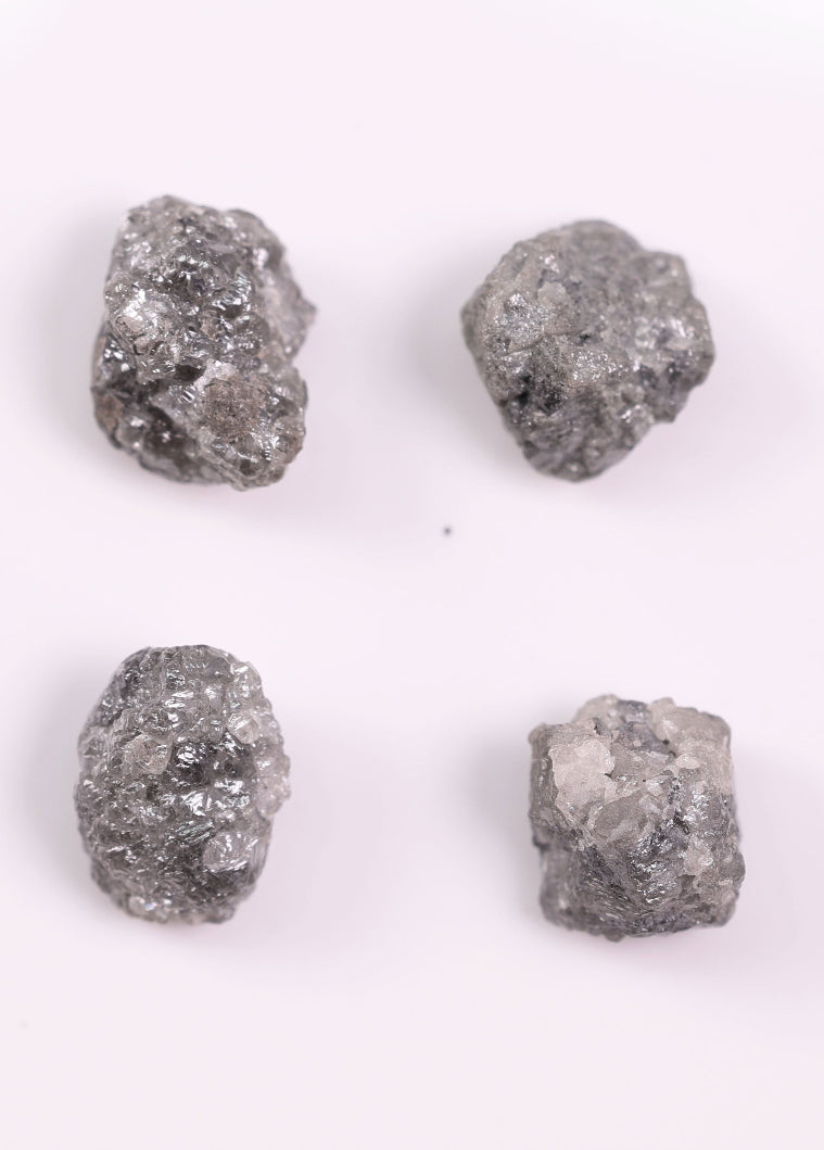 Four rough gray diamonds on a white background