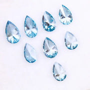 Eight vivid blue pear cut lab grown diamonds displayed on white background, featuring brilliant faceting, teardrop shape, and rich ocean blue tones ideal for custom engagement rings and fine jewelry.