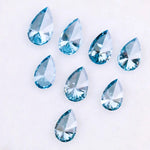 Eight vivid blue pear cut lab grown diamonds displayed on white background, featuring brilliant faceting, teardrop shape, and rich ocean blue tones ideal for custom engagement rings and fine jewelry.