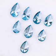 Eight vivid blue pear cut lab grown diamonds displayed on white background, featuring brilliant faceting, teardrop shape, and rich ocean blue tones ideal for custom engagement rings and fine jewelry.