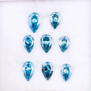 Eight vivid blue pear cut lab grown diamonds displayed on white background, featuring brilliant faceting, teardrop shape, and rich ocean blue tones ideal for custom engagement rings and fine jewelry.