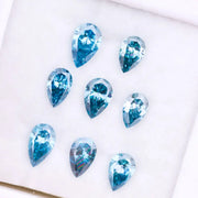 Eight vivid blue pear cut lab grown diamonds displayed on white background, featuring brilliant faceting, teardrop shape, and rich ocean blue tones ideal for custom engagement rings and fine jewelry.