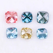 Six cushion cut lab grown diamonds in fancy colors including deep teal, vivid blue, pink, yellow, and light blue displayed on white background for fine jewelry design.