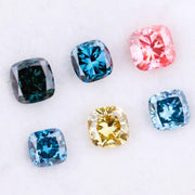 Six cushion cut lab grown diamonds in fancy colors including deep teal, vivid blue, pink, yellow, and light blue displayed on white background for fine jewelry design.