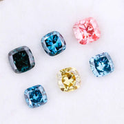 Six cushion cut lab grown diamonds in fancy colors including deep teal, vivid blue, pink, yellow, and light blue displayed on white background for fine jewelry design.