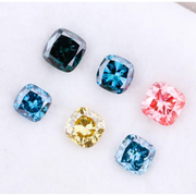 Six cushion cut lab grown diamonds in fancy colors including deep teal, vivid blue, pink, yellow, and light blue displayed on white background for fine jewelry design.