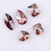 Five lab grown fancy color diamonds in red and cognac tones featuring pear, emerald, marquise, and trillion cuts displayed on a white background, loose sustainable gemstones for custom fine jewelry.
