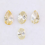 Four fancy yellow lab grown diamonds in pear and oval brilliant cuts displayed on white background, showcasing vivid yellow color, high clarity, and precision faceting.