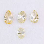 Four fancy yellow lab grown diamonds in pear and oval brilliant cuts displayed on white background, showcasing vivid yellow color, high clarity, and precision faceting.