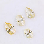Four fancy yellow lab grown diamonds in pear and oval brilliant cuts displayed on white background, showcasing vivid yellow color, high clarity, and precision faceting.