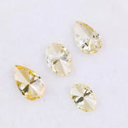 Four fancy yellow lab grown diamonds in pear and oval brilliant cuts displayed on white background, showcasing vivid yellow color, high clarity, and precision faceting.