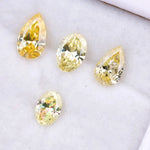 Four fancy yellow lab grown diamonds in pear and oval brilliant cuts displayed on white background, showcasing vivid yellow color, high clarity, and precision faceting.