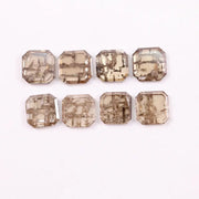 Emerald step cut lab grown diamonds with champagne tone and visible natural-style inclusions arranged in two rows on a white background.